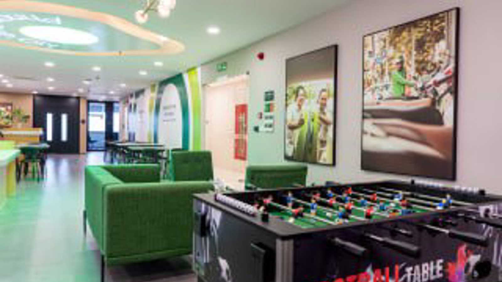a room with a foosball table and green couches