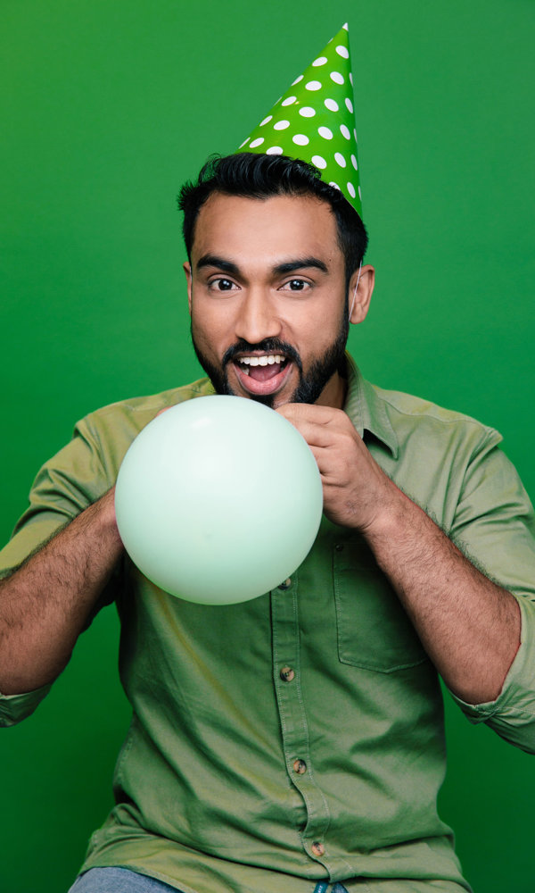 a man wearing a party hat and blowing a balloon