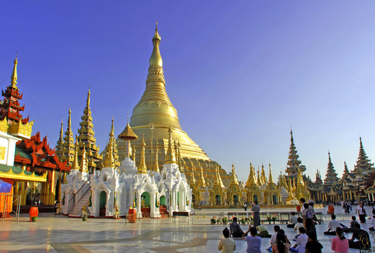 a group of people standing in front of a large gold and white building with Shwedagon Pagoda in the background
