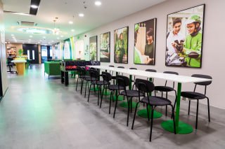 a long white table with black chairs and green tables