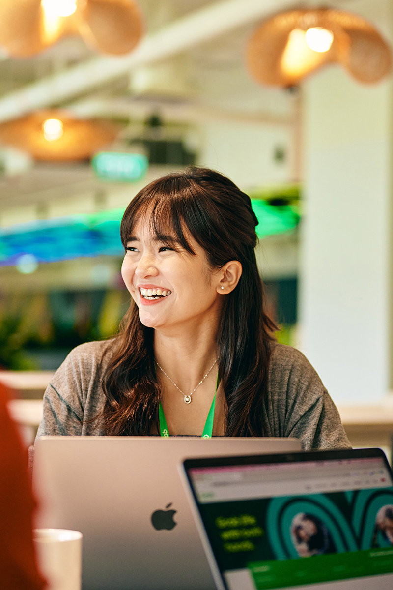 a woman smiling at a laptop