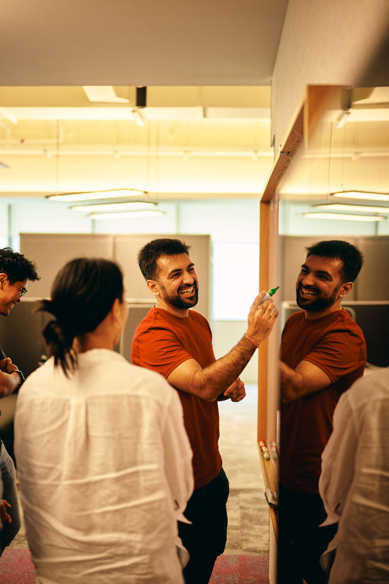 a group of people standing around a whiteboard