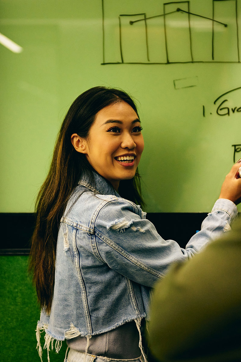 a woman writing on a whiteboard