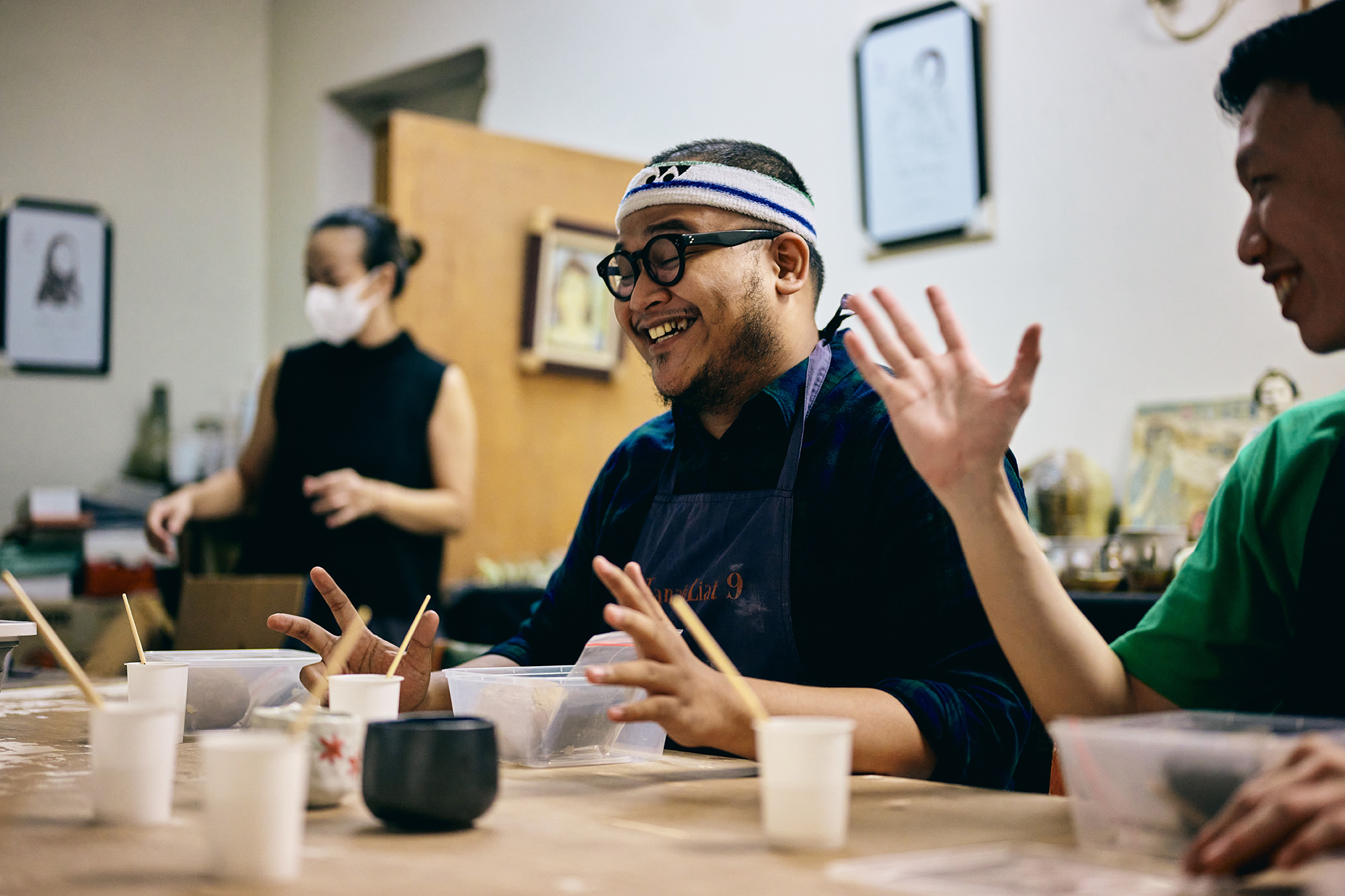 a man wearing glasses and a headband and holding his hands up