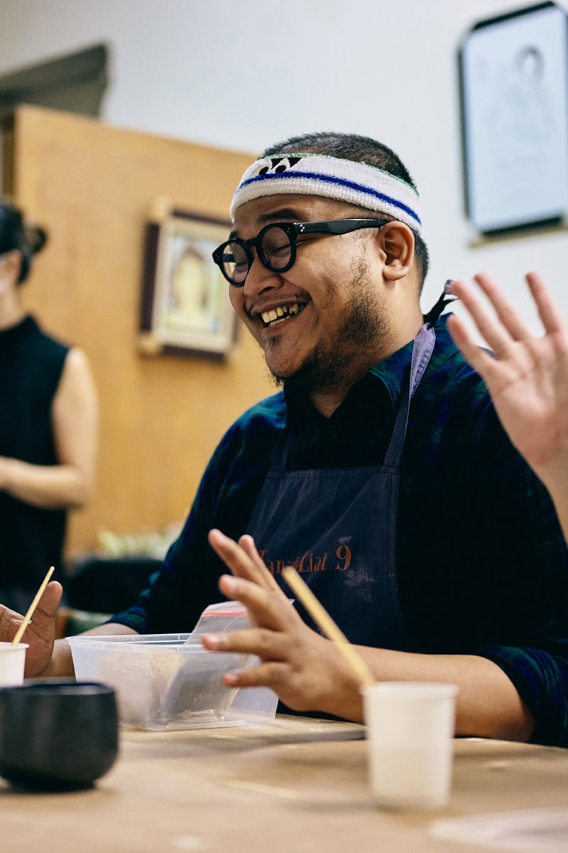 a man wearing glasses and a headband and holding his hands up