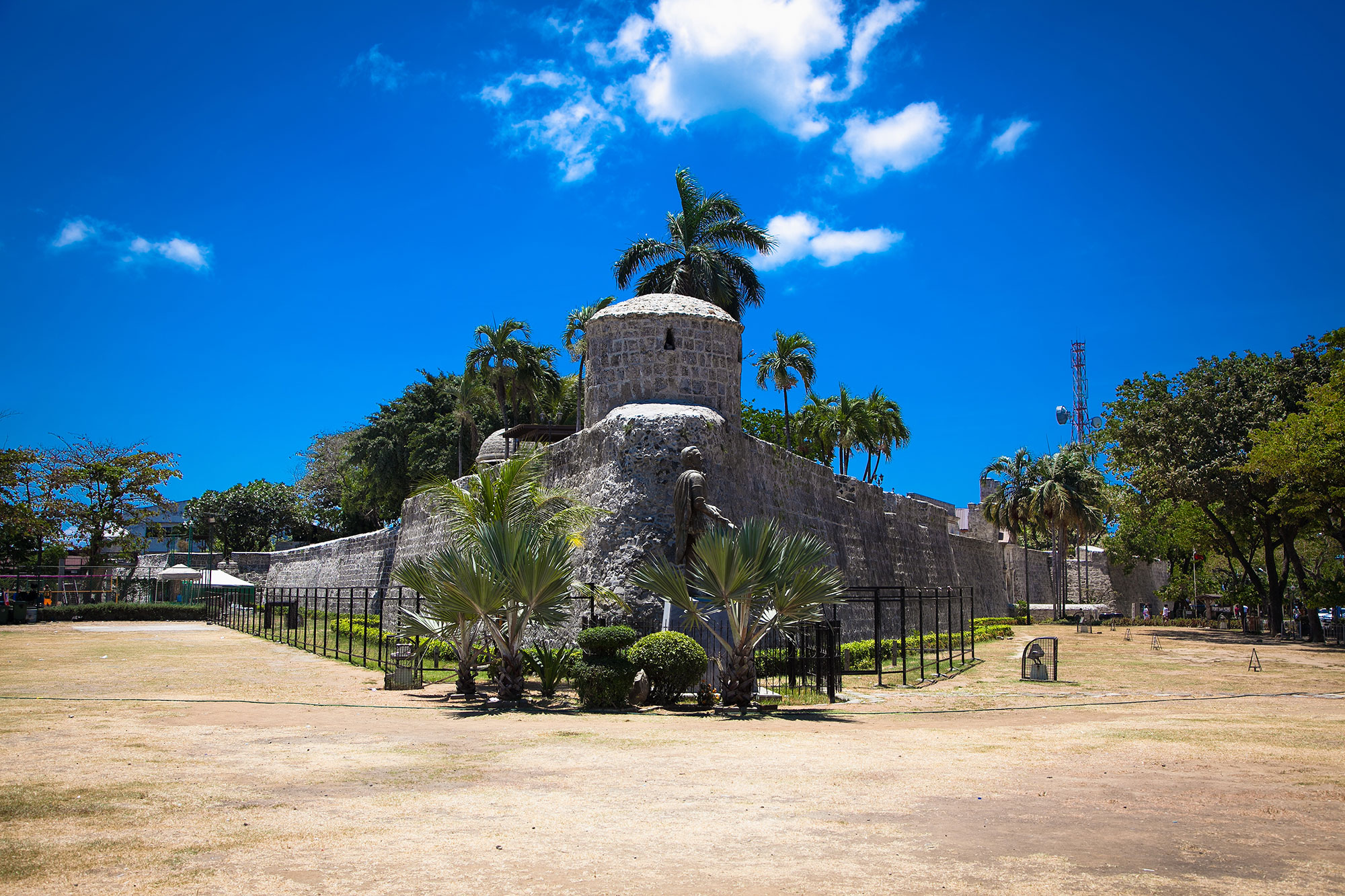 a stone building with a round tower and palm trees