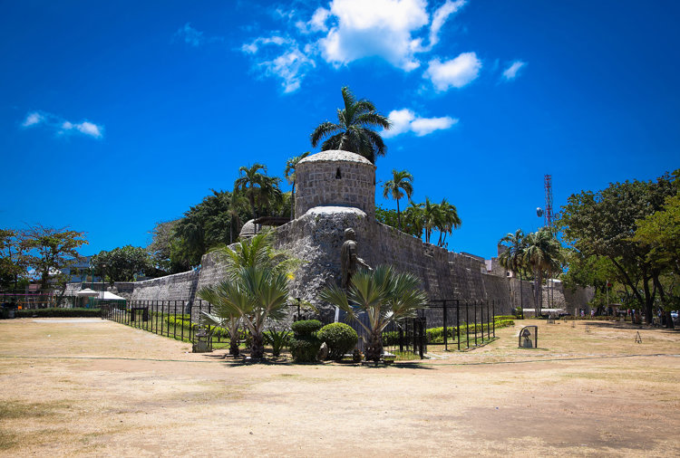 a stone building with a round tower and palm trees