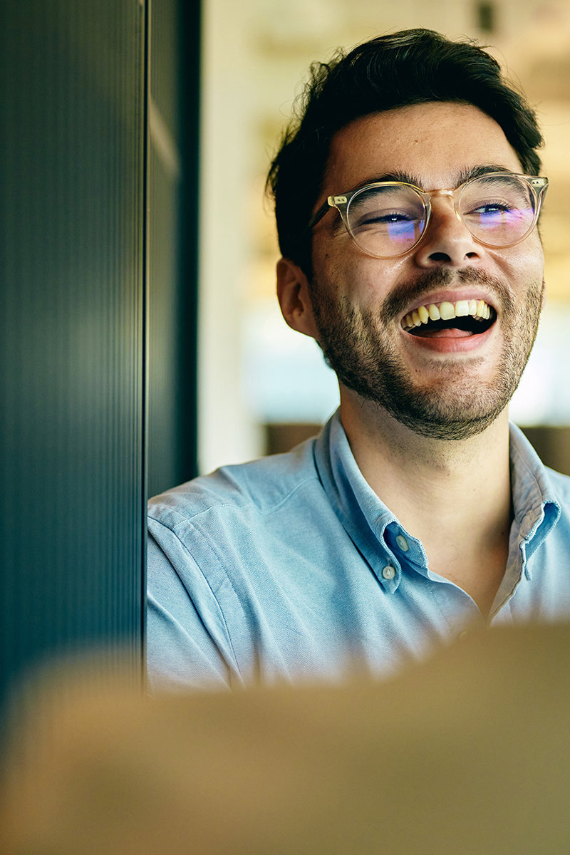 a man laughing while leaning against a wall