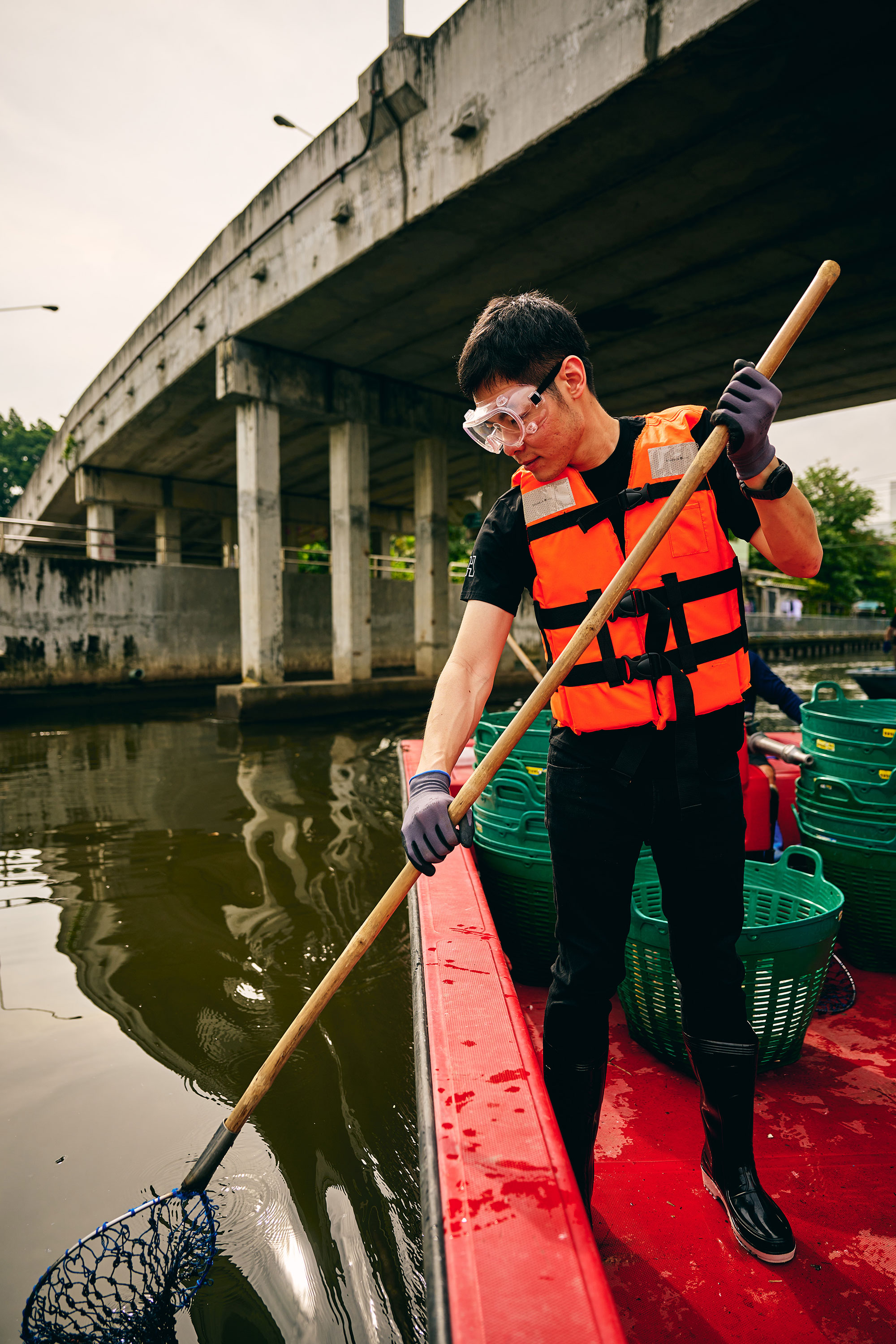 a man in a life jacket holding a stick on a boat
