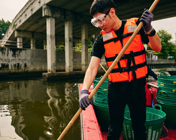 a man in a life jacket holding a stick on a boat