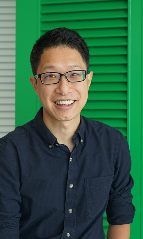 a man smiling in front of a green shutter