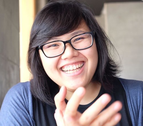 a woman smiling with her hand up