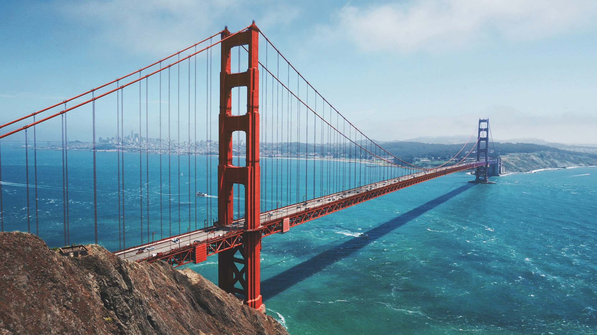 a red bridge over water with Golden Gate Bridge in the background