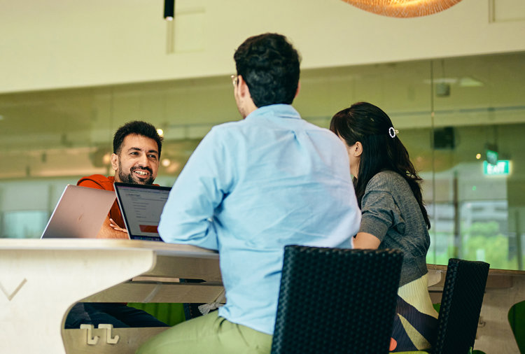 a group of people sitting at a table with laptops