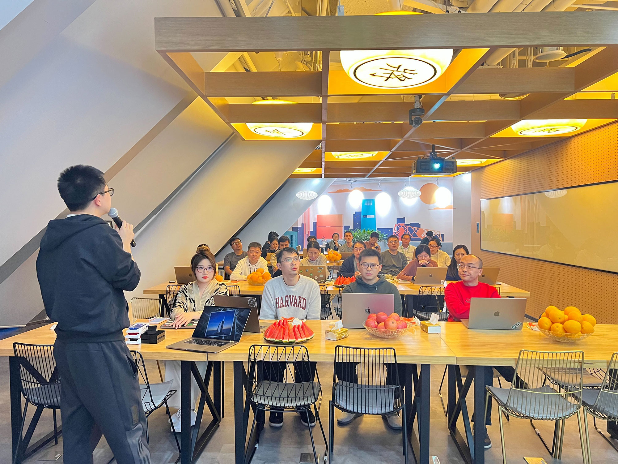 a man standing in front of a group of people sitting at tables with laptops