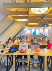 a man standing in front of a group of people sitting at tables with laptops
