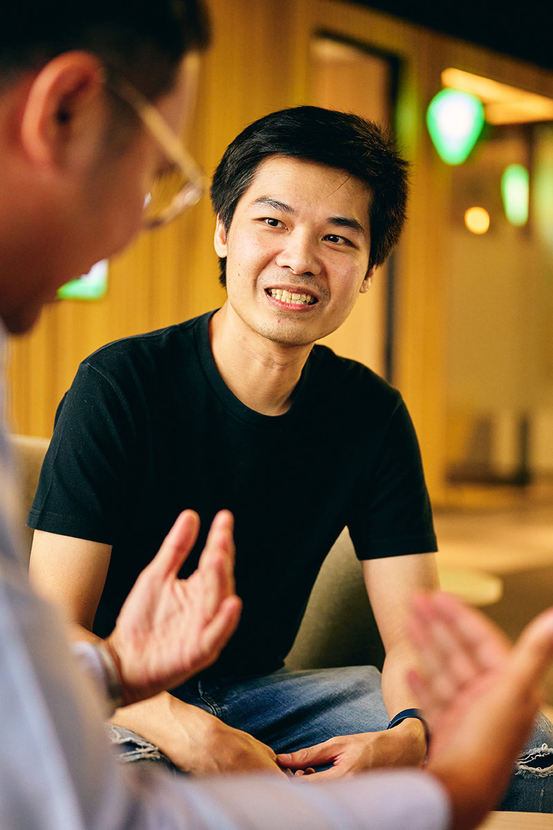 a man sitting in a chair talking to another man