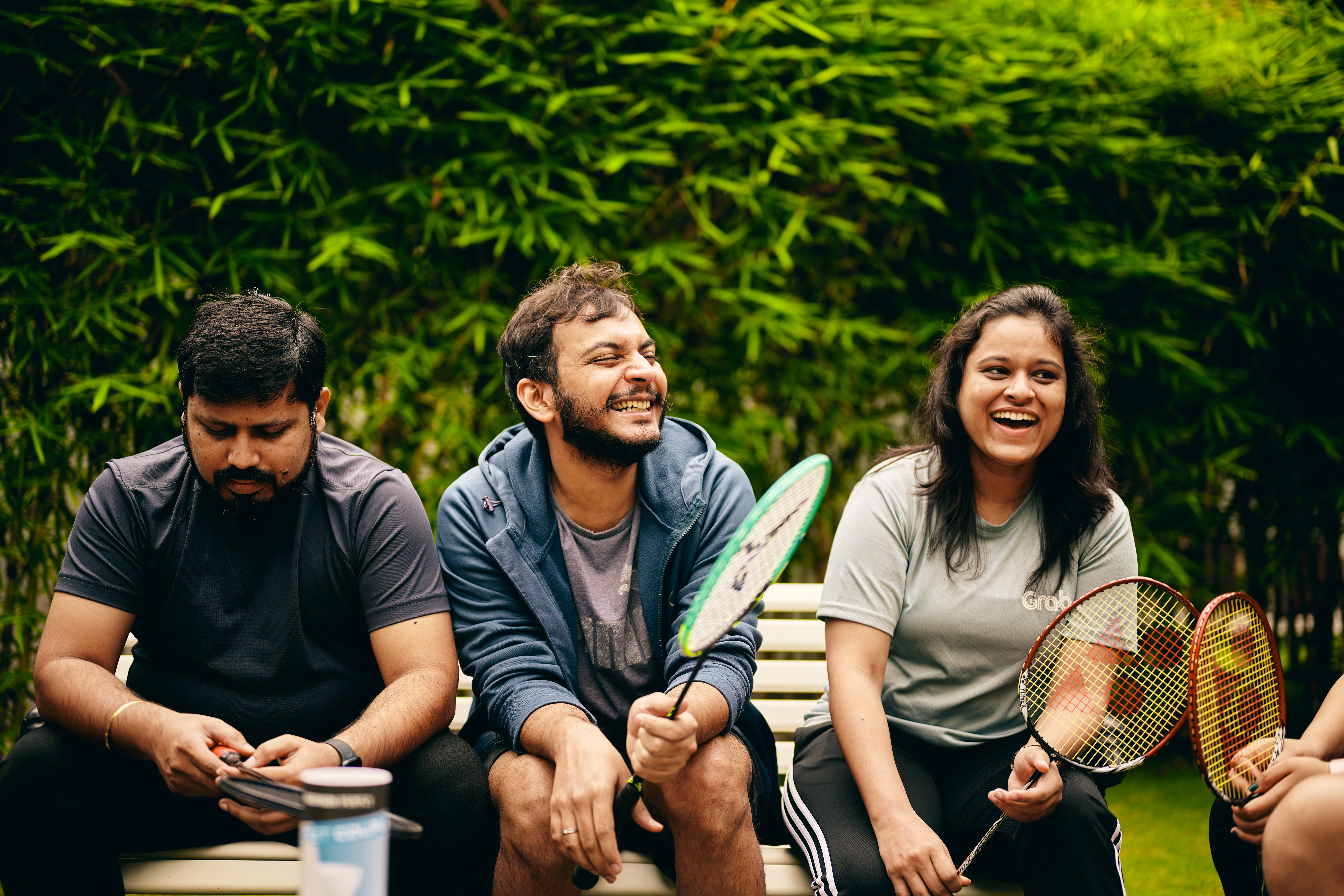 a group of people sitting on a bench with rackets