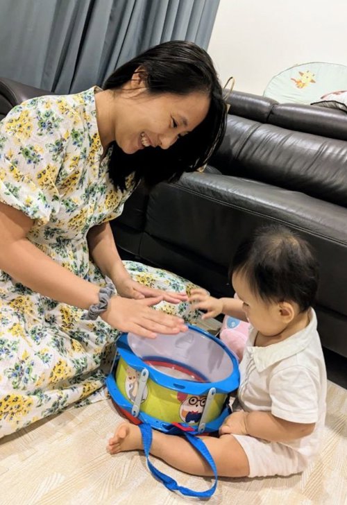 a person and baby playing with a drum