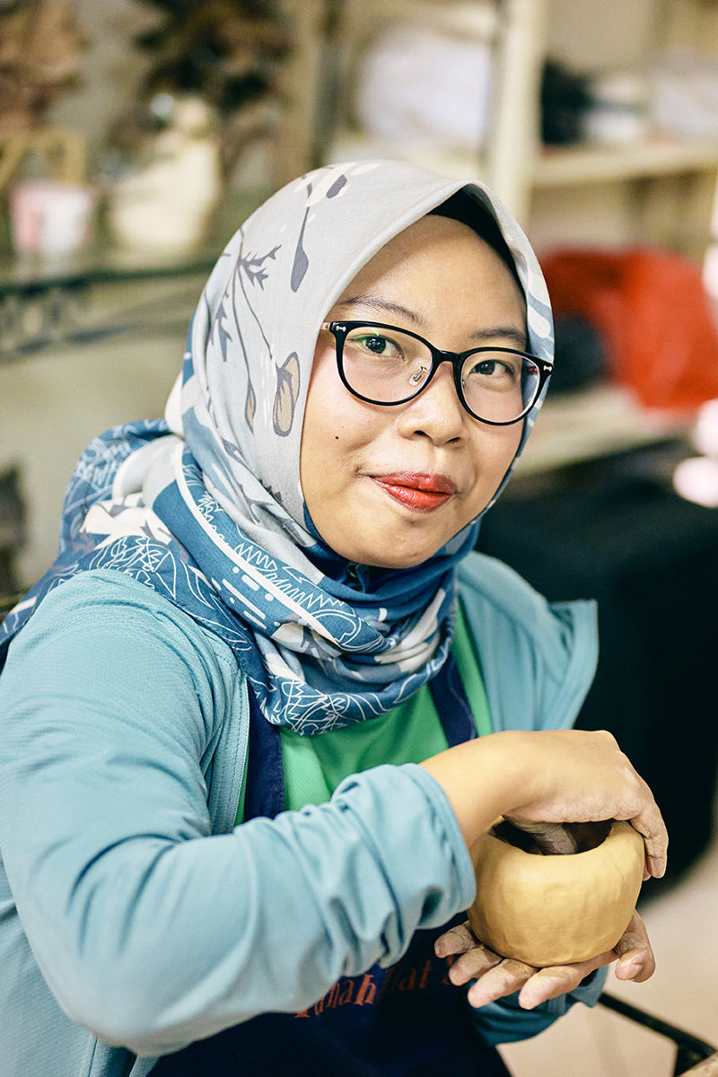 a woman holding a clay pot