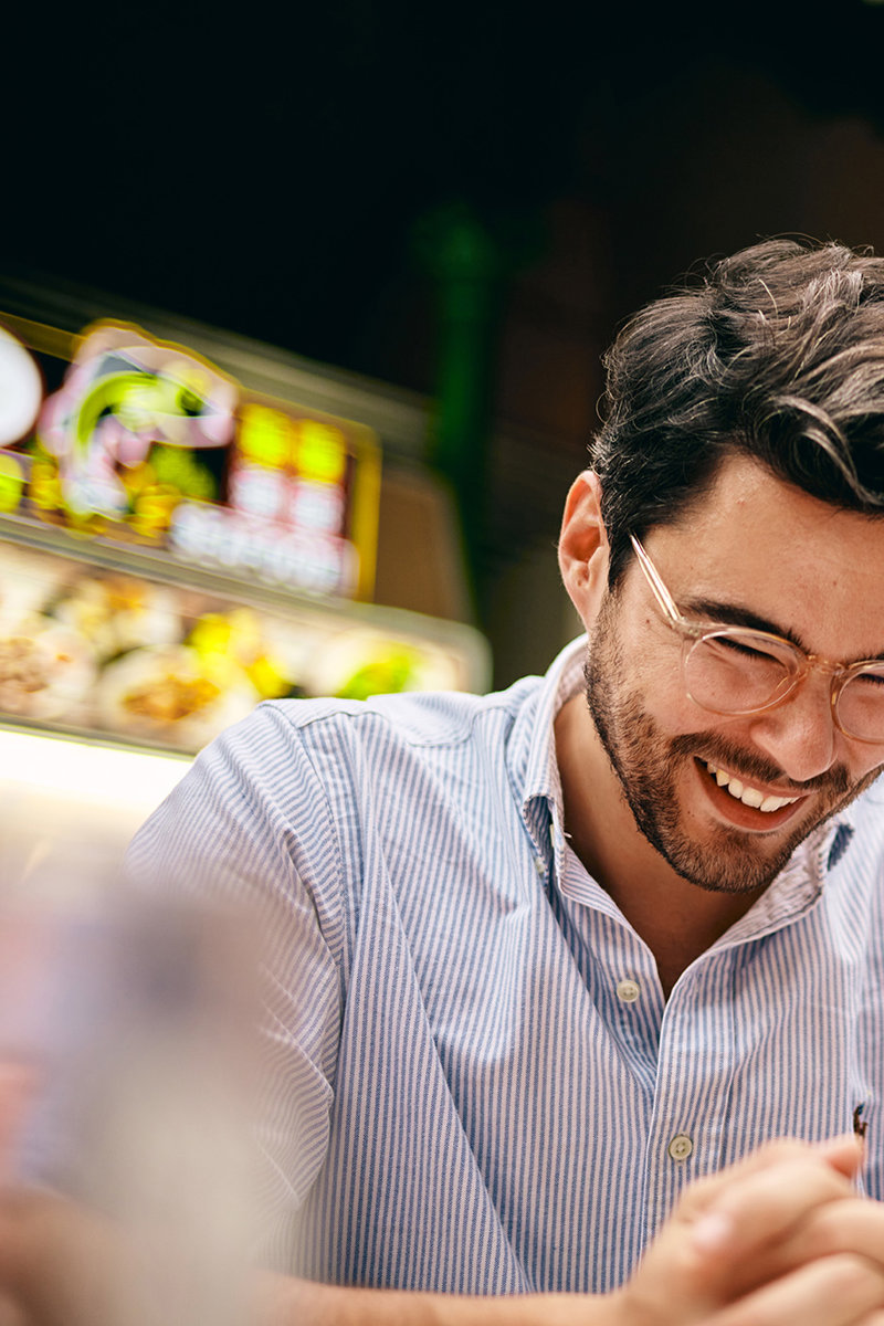 a man smiling while holding a cigarette