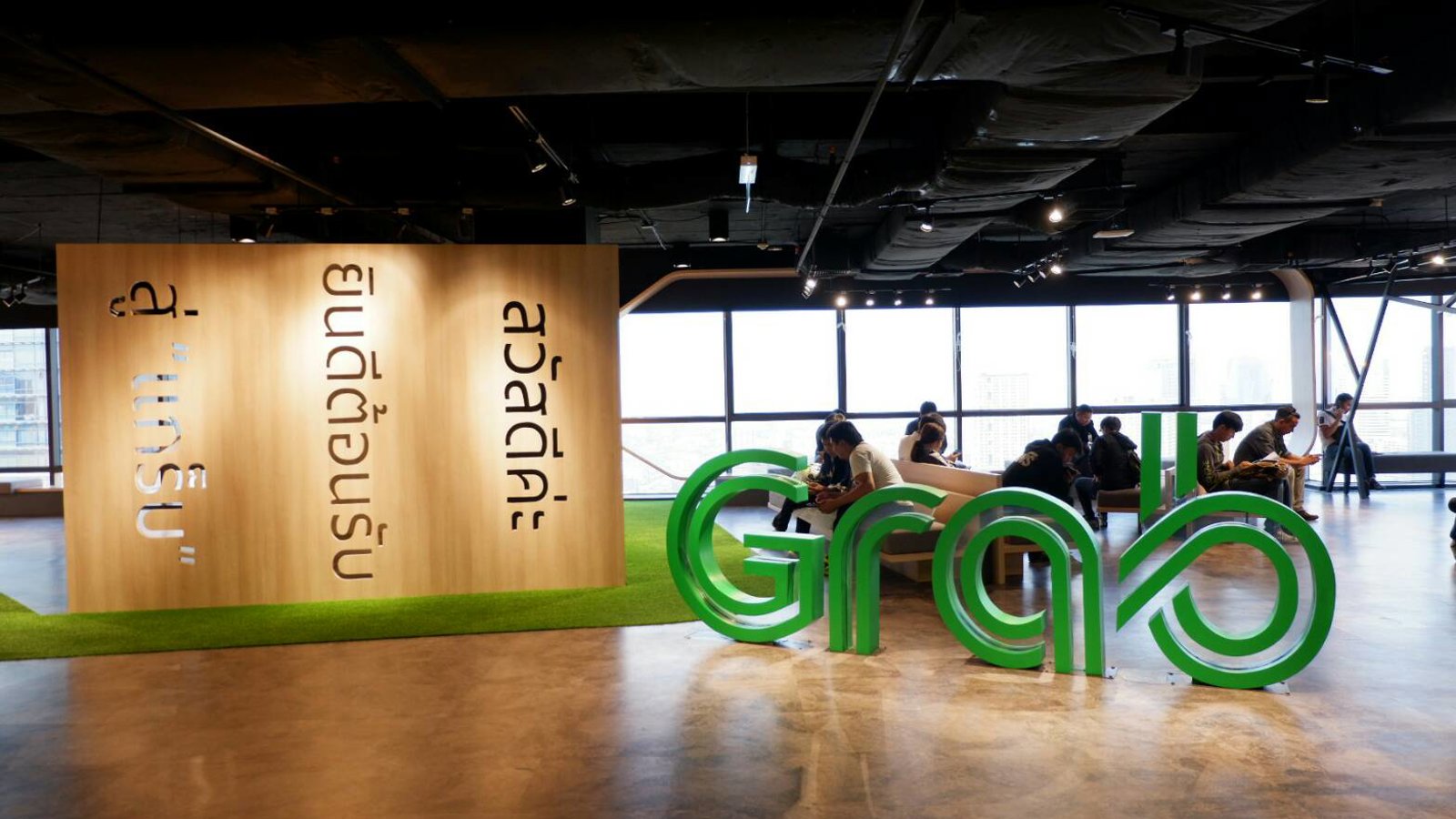 a group of people sitting in a room with large green letters