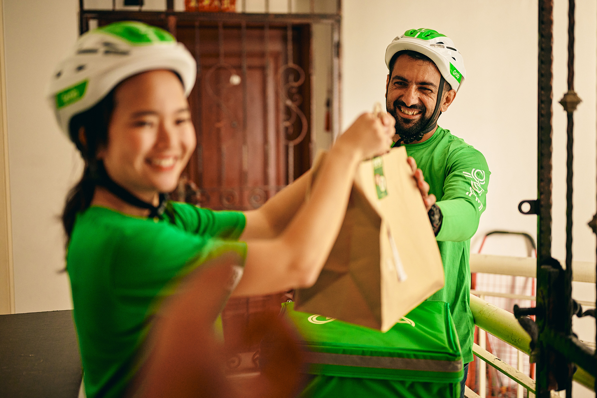 a man and woman wearing green shirts and holding a brown bag