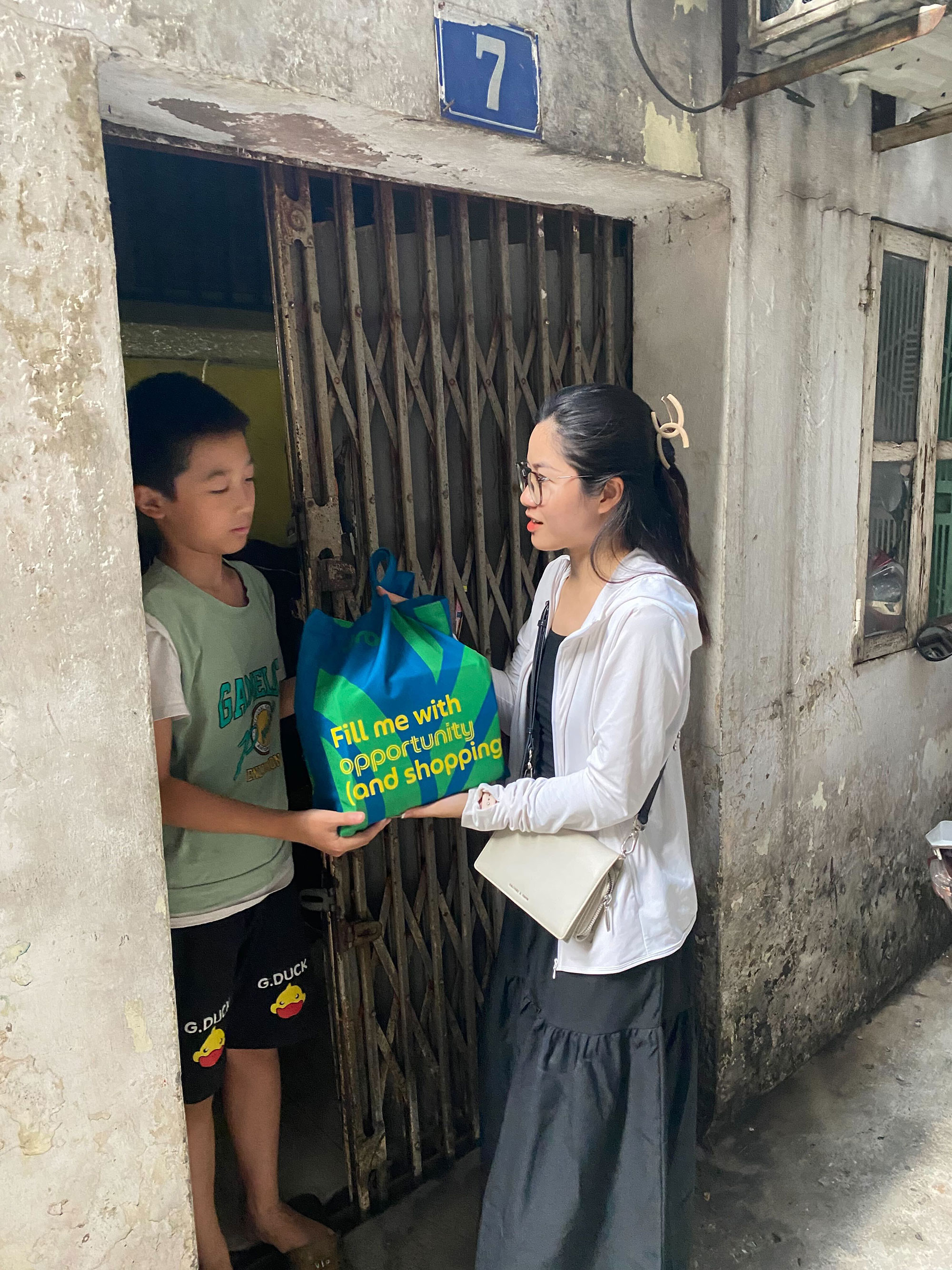 a woman holding a bag next to a boy
