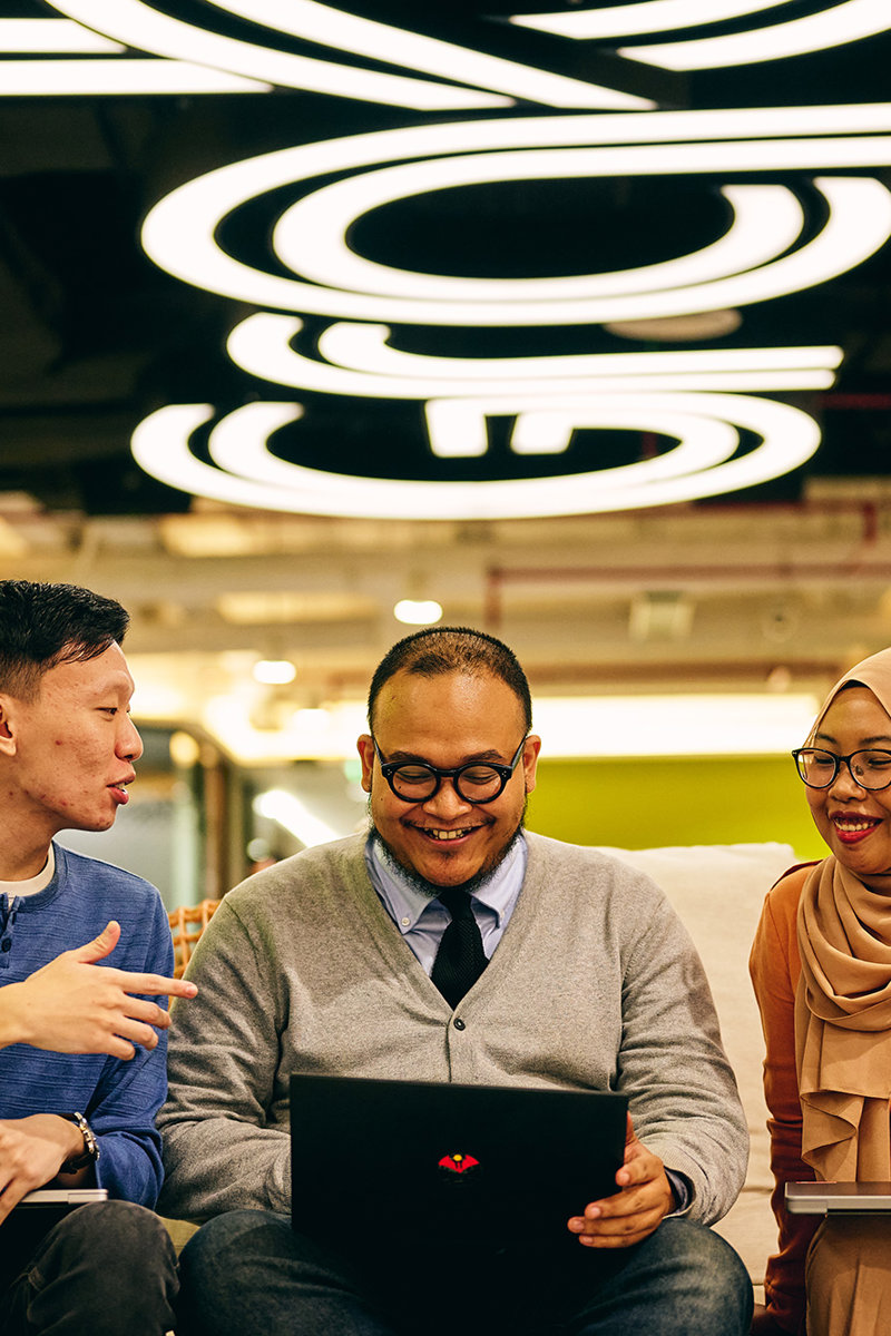 a group of people sitting on a couch with a laptop