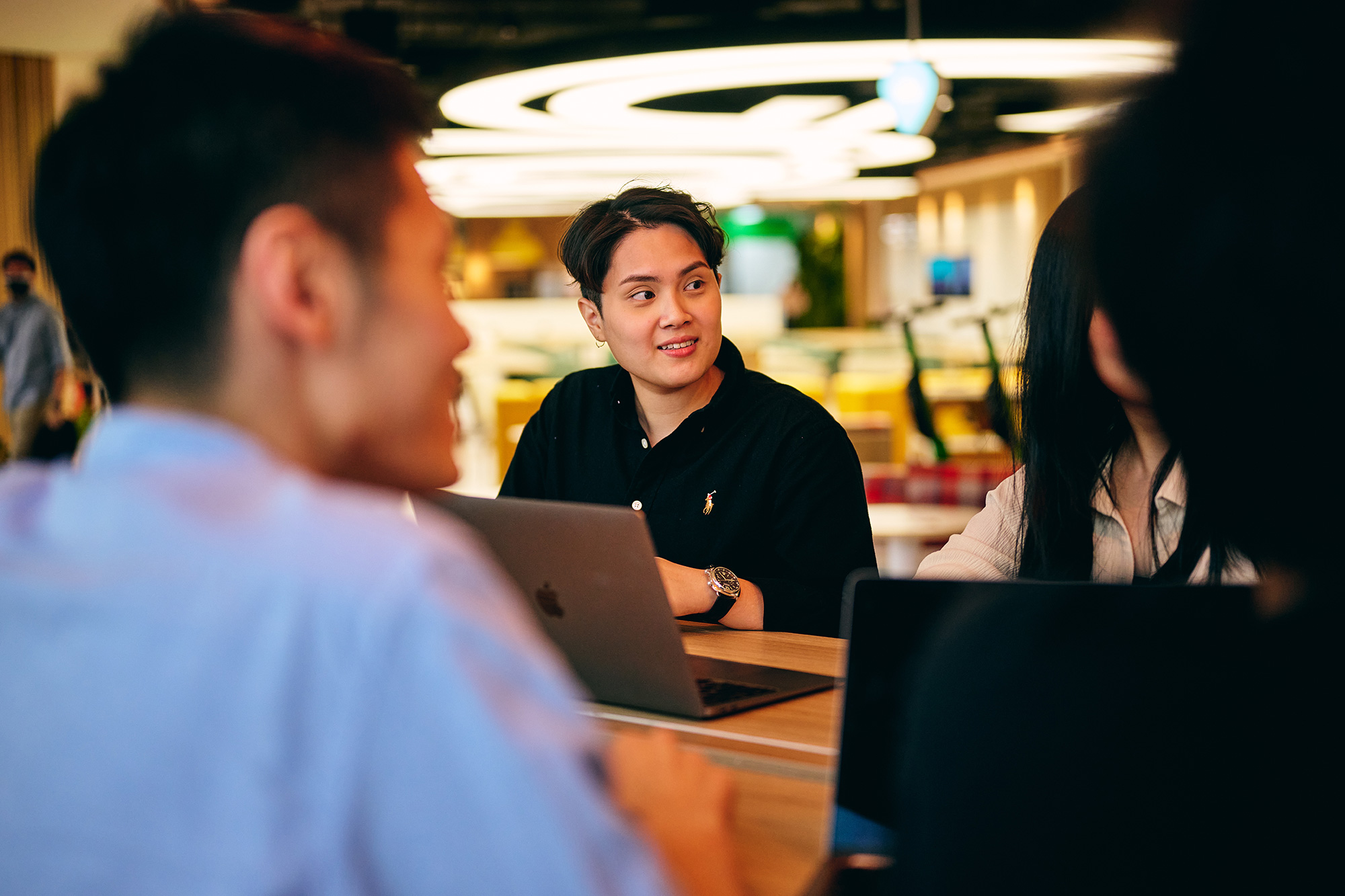 a group of people sitting at a table with laptops