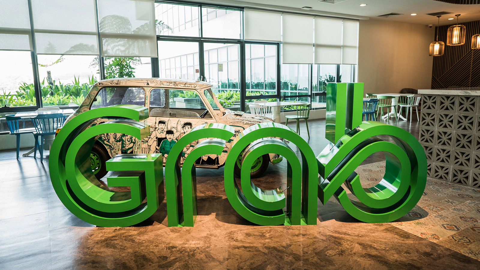 a large green letters in a room with a car in the background