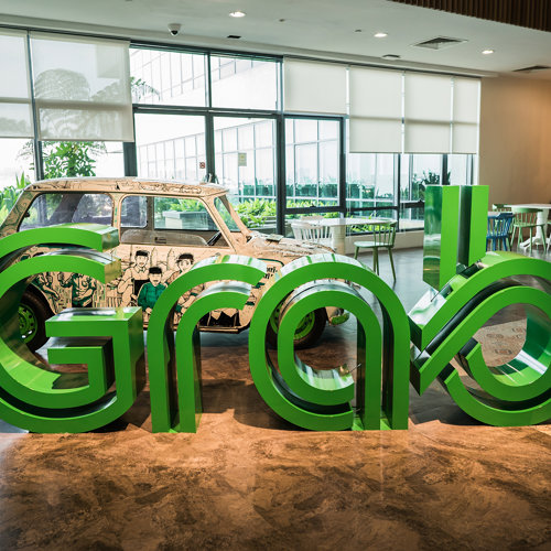a large green letters in a room with a car in the background
